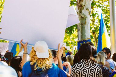 Madrid, İspanya 1 Temmuz 2024 Ukrayna 'ya destek için Ukrayna bayraklarıyla bir kalabalık protesto gösterisi düzenledi. Göçmenler bir gösteride boş tabela tutarak Rusya savaşı yüzünden destek veya protesto önerisinde bulunuyorlar..