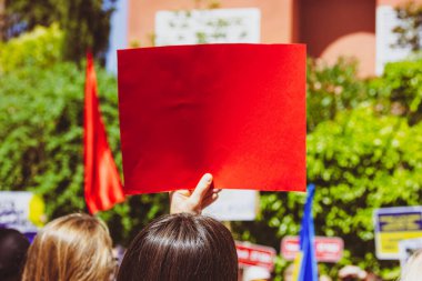 Madrid, İspanya 2 Temmuz 2024 Bir kişi protesto için kırmızı boş bir tabela tutuyor, mesajlaşma için mükemmel bir model. Diğer insanların ve bayrakların bulanık geçmişiyle gösteri sırasında elinde bir tabela tutan bir kadın.. 