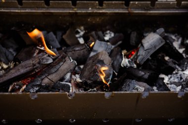 Izgara sezonu ve barbekü için alevlerle yanan kömür. Izgarada kömür yakmak, parlayan közleri ve alevleri göstermek yaz barbeküleri ve açık hava yemekleri için mükemmel..