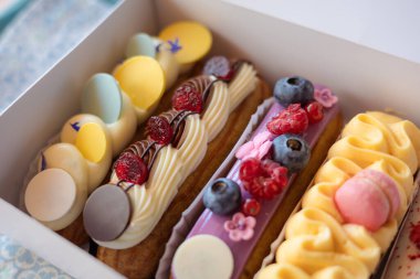 Taze böğürtlen ve kurabiye dolu nefis ekekler bir fırın kutusunda güzelce sergileniyor. Taze böğürtlen ve dekoratif kremayla süslenmiş renkli eklerdendir. Kremalı tatlılar ve ikramlar. 