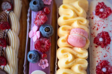 Taze böğürtlen ve kurabiye dolu nefis ekekler bir fırın kutusunda güzelce sergileniyor. Taze böğürtlen ve dekoratif kremayla süslenmiş renkli eklerdendir. Kremalı tatlılar ve ikramlar. 