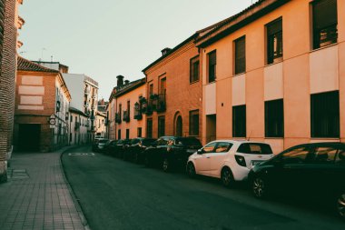 Alcala de Henares, İspanya 2 Kasım 2024 Avrupa caddesi park halindeki arabaları ve tarihi binaları ile. Küçük bir kasabada kaldırım kenarında park etmiş arabaların olduğu bir şehir manzarası. Sessiz mahalle