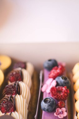 Taze böğürtlen ve kurabiye dolu nefis ekekler bir fırın kutusunda güzelce sergileniyor. Taze böğürtlen ve dekoratif kremayla süslenmiş renkli eklerdendir. Kremalı tatlılar ve ikramlar. 