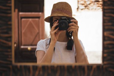 Madrid, İspanya 1 Haziran 2024. Güneş şapkalı bir turist elinde fotoğraf makinesi, kendi portresini çekiyor. Yeşil gözlü genç bir kadın, hasır şapka takıyor, elinde kamera, ve izleyiciye bakıyor..