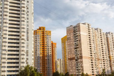 Kyiv, Ukrayna. 7 Haziran 2025 Bulutlu bir gökyüzüne karşı bir grup bina şehir manzarası yaratıyor. Gökyüzünün altında birçok penceresi olan uzun bir apartman. Arka planda başka binalar da görünüyor..