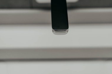 Zarif, modern krom bir musluk, parlak bir arka planda, şık, modern bir musluğa karşı minimalist bir banyoda. Cilalanmış krom, ışığı yansıtarak temiz bir estetik yaratıyor..