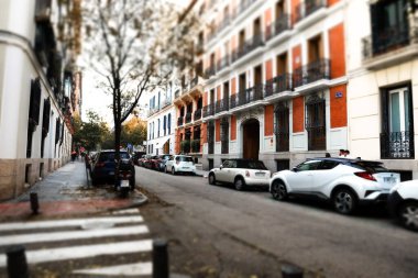Madrid, İspanya, 8 Kasım 2024 büyüleyici bir sokak mimarisi yol boyunca park etmiş arabalarla güzel bir mimari sergiliyor. Binaların sokak manzarası, yaya geçidi ve çıplak ağaçlar. Sonbahar kenti
