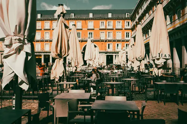 Madrid, İspanya 1 Mayıs 2024 Avrupa 'nın ana meydanında bir açık kafe güneşli bir günde masalar, şemsiyeler. Masaları olan bir İspanyol başkentinde açık bir kafe. Turuncu bina bir arka plan. Plaza Belediye Başkanı 