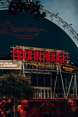 Berlin, Almanya. 2 Ekim 2024 Moulin Rouge Kabare tabelası. Eğlence ve kültür. Canlı bir çekim ikonik Moulin Rouge işaretini yakalar, kırmızı ışıkta karanlık gökyüzüne, efsanevi bir müzikale karşı.. 