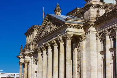 Berlin, Almanya 2 Ekim 2024 Reichstag binası mavi gökyüzüne karşı dimdik ayakta duruyor. Berlin, Almanya 'daki Reichstag binası, tarihi mimarisini sütunları ve parlak mavi gökyüzü ile sergiliyor..