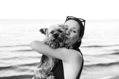 Küçük Yorkshire teriyeri köpeğine sarılıp öpen genç bir kadının narin portresi. Aşkı, ilgiyi, dostluğu ve hayvan bağını gösteren özgün duygusal bir an. Yaşam tarzı ve evcil hayvan temaları için mükemmel. 