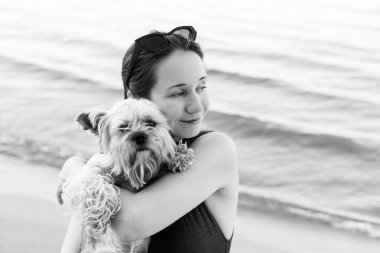 Küçük bir Yorkshire teriyeri köpeğine sarılan genç bir kadının narin portresi. Aşkı, ilgiyi, dostluğu ve hayvan bağını gösteren özgün duygusal bir an. Yaşam tarzı ve evcil hayvan temaları için mükemmel. Şirin köpek.