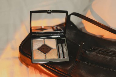 Paris, Fransa 2 Mayıs 2025 Dior göz falı paleti ve yumuşak, sıcak bir arka planda siyah deri çanta. Şık bir siyah deri çantanın yanında lüks bir göz falı, sofistike bir kompozisyon..