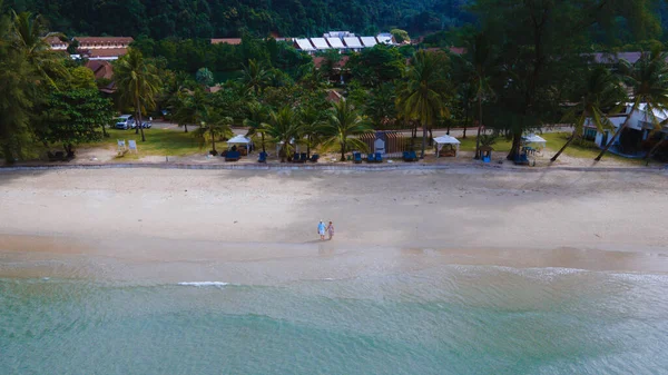 stock image Couple of men and women walking on the beach during sunset, Drone aerial view at the Klong Prao Beach in Koh Chang, drone view from above at turquoise colored ocean. 