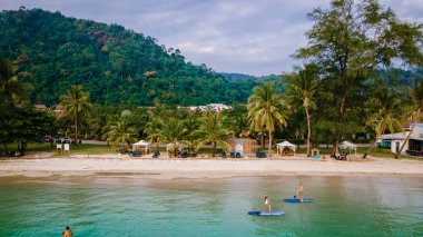 Erkekler ve kadınlar Koh Chang Tayland 'da bir yemek masasında kürek çekiyorlar. stand-up pedalları