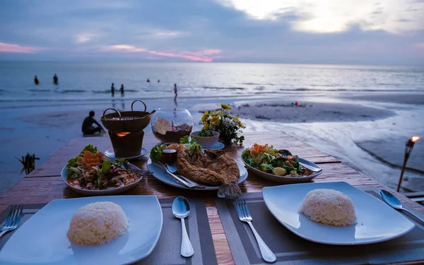 stock image Dinner during sunset with fish and Thai food.Dinner on the beach during sunset