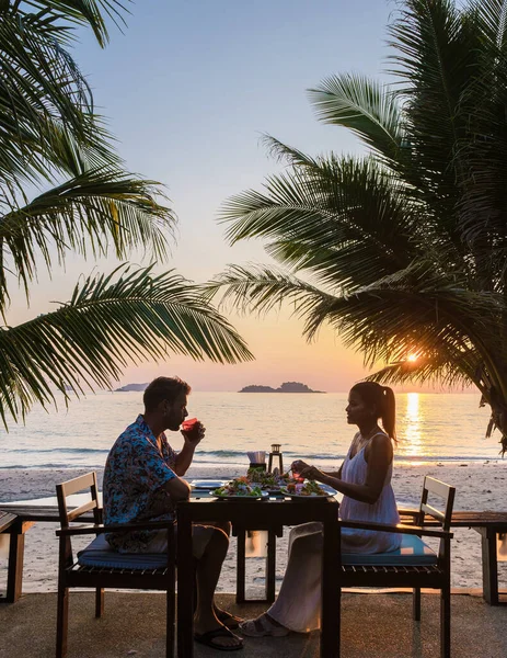 Romantic dinner during sunset on a tropical beach in Thailand, Koh Chang island. Men and women honeymoon dinner during sunset