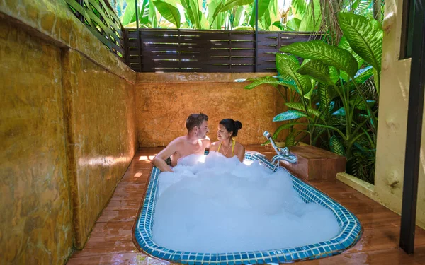 度假期间 一对情侣在一座豪华别墅的热带雨林花园的浴缸里洗澡 室外浴缸中的男女 — 图库照片