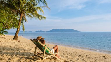Asyalı Taylandlı kadınlar Klong Kloi Beach Koh Chang Tayland 'da plaj sandalyesinde gün batımını izliyorlar.. 