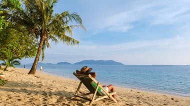 Asyalı Taylandlı kadınlar Klong Kloi Beach Koh Chang Tayland 'da plaj sandalyesinde gün batımını izliyorlar.. 