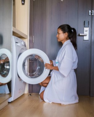 Kadınlar çamaşırları makineye koyarak çamaşır yıkarlar. Çamaşır makinesi olan kadınlar çamaşırlarını yıkıyor.