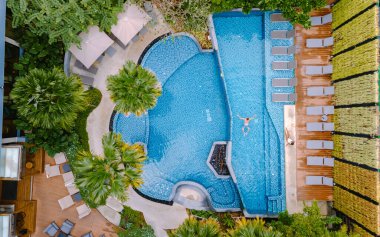 Havuzun yukarısından drone görüntüsü. Havuz manzaralı birkaç erkek ve kadın havuz başında