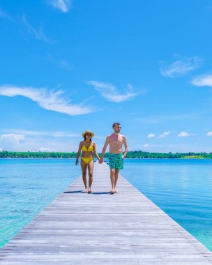 Tayland 'da tropik bir adada tahta bir tahtanın üzerinde yürüyen çift, Koh Mak Trat yakınlarındaki Koh Kham, tropik bir adada tahta bir iskele.