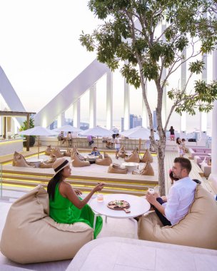 Gün batımında şehrin tepesindeki bir restoranda yemek yiyen bir çift erkek ve kadın. 