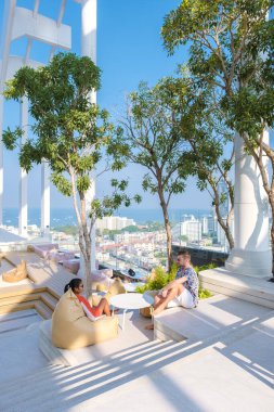 Lüks bir otelin çatısındaki iki kadın ve erkek tatil sırasında şehrin siluetine bakıyorlar.. 