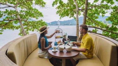 Tropikal ada Phuket Tayland 'da bir kuş ağında öğleden sonra çayı. Bir çift erkek ve kadın kuş ağında çay içiyorlar.