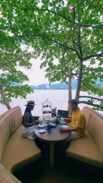 在泰国热带岛屿普吉岛的树上 一对男女在一个鸟网篮子里享用下午茶 — 图库视频影像