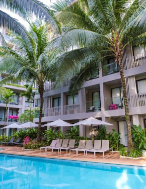 Phuket Tayland Kasım 2022, Palmiye ağaçları ve plaj sandalyeleri ve güneşli yataklı yüzme havuzlu lüks konut