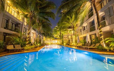 Phuket Tayland Kasım 2022, Palmiye ağaçları ve plaj sandalyeleri ve güneşli yataklı yüzme havuzlu lüks konut