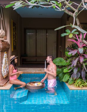 Tatil sırasında havuzda kahvaltı yapan bir çift ve havuzda yüzen kahvaltı yapan kadınlar.. 