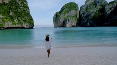 Koh Phi Phi Tayland, Asyalı Taylandlı kadınlar sabahları Maya Körfezi sahilinde turist olmadan yürüyorlar.