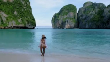 Koh Phi Phi Tayland, Asyalı Taylandlı kadınlar sabahları Maya Körfezi sahilinde boş bir plajda yürüyorlar.