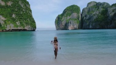 Maya plajı, Koh Phi Phi Tayland, Maya Körfezi sahilinde yürüyen şapkalı Asyalı Taylandlı kadınlar.. 