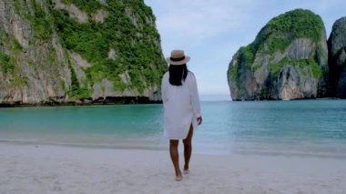 Maya plajı, Koh Phi Phi Tayland, Maya Körfezi sahilinde yürüyen şapkalı Asyalı Taylandlı kadınlar.. 