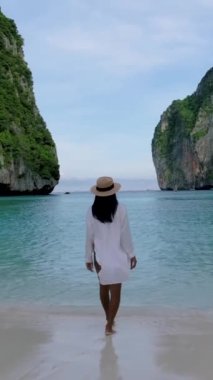 Maya plajı, Koh Phi Phi Tayland, Maya Körfezi sahilinde yürüyen şapkalı Asyalı Taylandlı kadınlar.. 