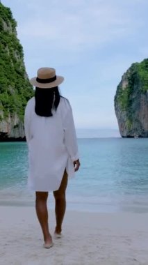 Maya plajı, Koh Phi Phi Tayland, Asyalı Taylandlı kadınlar, Maya Körfezi sahilinde sabahın erken saatlerinde yürüyorlar.
