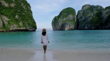 Koh Phi Phi Tayland, Asyalı Taylandlı kadınlar sabahları Maya Körfezi sahilinde boş bir plajda yürüyorlar.