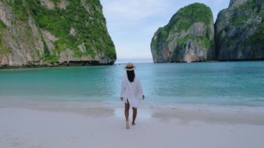 Koh Phi Phi Tayland, Asyalı Taylandlı kadınlar sabahları Maya Körfezi sahilinde turist olmadan yürüyorlar.