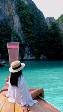 Koh Phi Phi Tayland 'da yeşil zümrüt okyanuslu Pileh Lagoon, uzun kuyruklu bir teknenin önündeki kadınlar.
