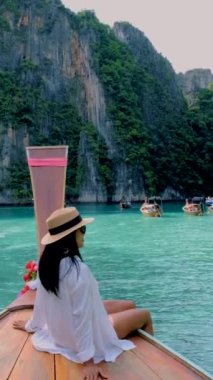 Koh Phi Phi Tayland 'da yeşil zümrüt okyanuslu Pileh Lagoon, uzun kuyruklu teknenin önündeki kadınlar.