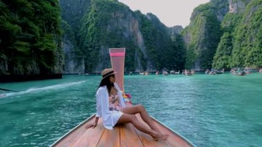 Koh Phi Phi Tayland 'da yeşil zümrüt okyanuslu Pileh Lagoon, uzun kuyruklu bir teknenin önündeki kadınlar.