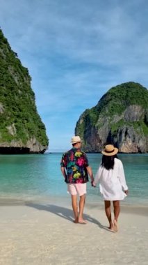 Sabahın erken saatlerinde Koh Phi Phi Tayland sahillerinde turist olmayan boş Maya plajı. Sahilde yürüyen bir çift kadın ve erkek.