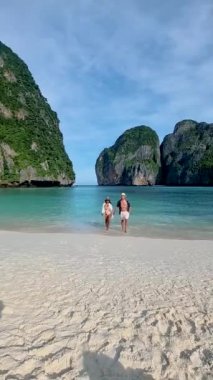 Birkaç erkek ve kadın sahilde yürüyor, sabahın erken saatlerinde Koh Phi Tayland 'da turist olmadan boş Maya plajında.. 