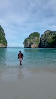 Koh Phi Phi Tayland sahilinde yürüyen şapkalı adamlar. Maya Körfezi 'ndeki Tayland' ın ünlü plajı.