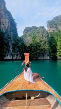 Taylandlı kadınlar Pileh Lagoon 'da uzun kuyruklu bir teknenin önünde yeşil zümrüt okyanusla Koh Phi Tayland' da, kadınlar uzun kuyruklu bir teknenin önünde.