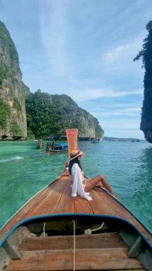Koh Phi Phi Tayland, Taylandlı kadınlar Pileh lagünündeki uzun kuyruklu teknenin önünde yeşil zümrüt okyanusla Koh Phi Tayland 'da, uzun kuyruklu bir teknenin önünde kadınlar.